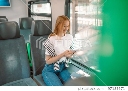 Portrait of a smiling lovely girl typing message on mobile phone in subway train 97183671