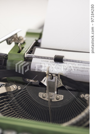 Vintage green typewriter machine with a sheet of paper and generic text typed 97184280