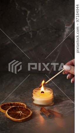 A woman hand holds a long match to light a homemade candle 97184944