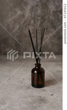 Aromatic reed diffuser bottle with black sticks on a dark marble background 97185012