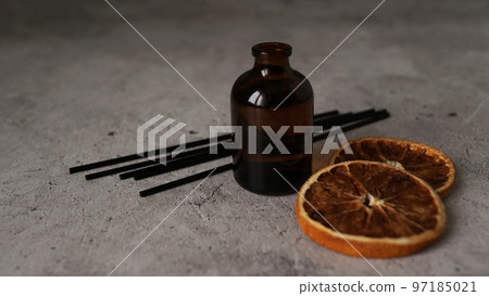 Citrus reed diffuser on dark background. Bottle, sticks and dry oranges 97185021