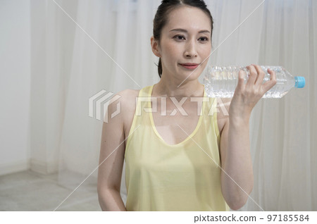 Woman training with plastic bottle dumbbells 97185584