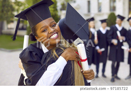 Two happy female students hugging during graduation ceremony at college or university. 97185722