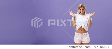 Studio shot of woman having mental breakdown screaming out loud shaking raised palms closing eyes and bending head down feeling scared and yelling from fear over purple background 97186627