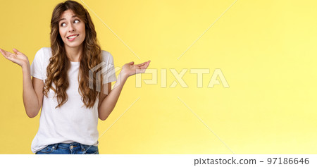 Sorry cannot help you. Silly awkward cute pretty woman curly long hair shrugging glancing away embarrassed say oops apologizing shrugging unaware clueless indifferent unwilling deal situation 97186646