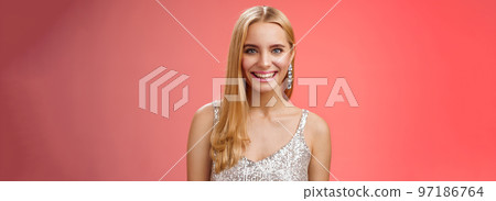 Charming glamour fabulous adult 25s blond woman in elegant silver dress shiny earrings smiling happily take part interesting conversation talking look friendly grinning, standing red background Charming glamour fabulous adult 25s blond woman in elegant silver dress shiny earrings smiling happily take part interesting conversation talking look friendly grinning, standing red background 97186764
