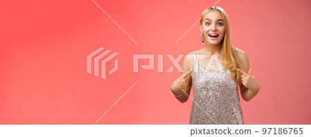 Surprised wondered happy blond charming cheerful woman in glittering silver dress pointing herself amused thrilled picked be chosen participate awesome event, standing joyful red background 97186765