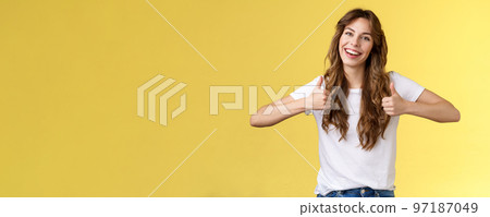 Outgoing positive confident lively young girl long curly haircut support great effor show thumbs up positive reply approving good choice like your outfit smiling broadly yellow background Outgoing positive confident lively young girl long curly haircut support great effor show thumbs up positive reply approving good choice like your outfit smiling broadly yellow background 97187049