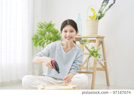 Portrait of a woman doing DIY indoors with an electric screwdriver Portrait of a woman doing DIY indoors with an electric screwdriver 97187074