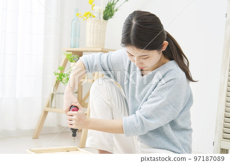 A woman doing DIY indoors using an electric screwdriver A woman doing DIY indoors using an electric screwdriver 97187089