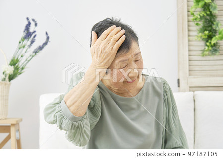 Elderly woman with a headache at home 97187105