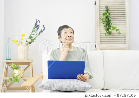 Elderly woman thinking while using a computer at home Elderly woman thinking while using a computer at home 97187109