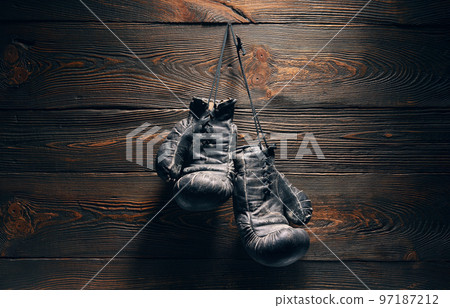 Old boxing gloves hanging on nail on wooden wall Old boxing gloves hanging on nail on wooden wall 97187212