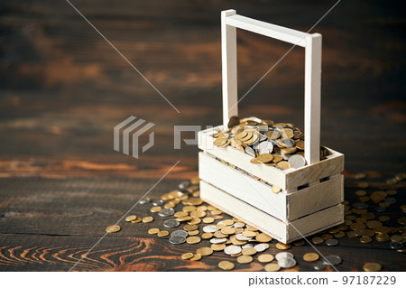 Basket filled with pile of coins with copy space for text on wooden background 97187229