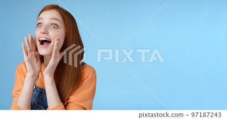 Attractive silly european redhead young girl 20s calling friend searching someone crowd look relaxed joyfully yelling hold hands opened mouth shouting name louder look left, blue background Attractive silly european redhead young girl 20s calling friend searching someone crowd look relaxed joyfully yelling hold hands opened mouth shouting name louder look left, blue background 97187243
