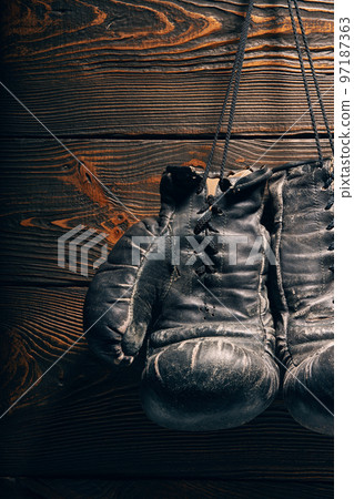 Old boxing gloves hanging on nail on wooden wall. Old boxing gloves hanging on nail on wooden wall. 97187363