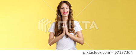 Cheerful confident outgoing young polite girl say namaste greeting asian guests smiling gladly thanking for visit hold hands pray supplication gesture asking favour begging stand yellow background Cheerful confident outgoing young polite girl say namaste greeting asian guests smiling gladly thanking for visit hold hands pray supplication gesture asking favour begging stand yellow background 97187364