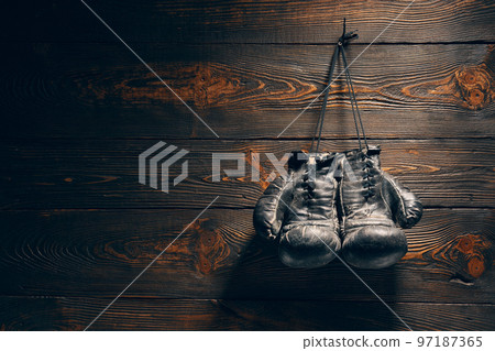 Old boxing gloves hang on nail on wooden wall with copy space for text Old boxing gloves hang on nail on wooden wall with copy space for text 97187365