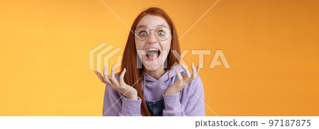 Shocked excited overwhelmed young screaming happy redhead girl wearing glasses winning hear excellent news yelling out loud rejoicing unbelievable luck raising hands spread stare surprised Shocked excited overwhelmed young screaming happy redhead girl wearing glasses winning hear excellent news yelling out loud rejoicing unbelievable luck raising hands spread stare surprised 97187875