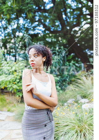 Young African American multiracial woman in midi pencil skirt with front button slit in park or street outdoor. White t shirt mock up. Fall season Young African American multiracial woman in midi pencil skirt with front button slit in park or street outdoor. White t shirt mock up. Fall season 97188312