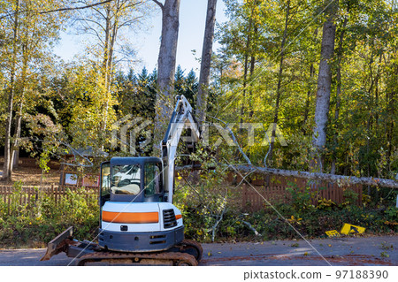 Several trees were uprooted during recent tornado that caused tractor to be brought in clean up trees mess. Several trees were uprooted during recent tornado that caused tractor to be brought in clean up trees mess. 97188390