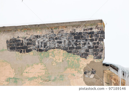 A shabby wall with burnt bricks and icicles on the edge. A shabby wall with burnt bricks and icicles on the edge. 97189146