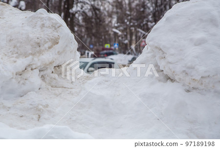A huge, white snowdrift, in the middle you can see the city street in defocus.  97189198