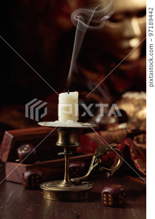Extinguished candle, dice, and carnival masks on an old wooden table. Extinguished candle, dice, and carnival masks on an old wooden table. 97189442