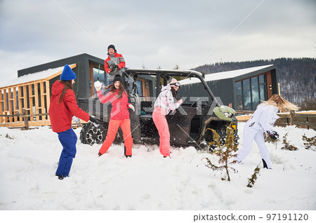 Happy women having fun in snow. Off-road buggy car on background. Concept of active leisure and winter activities. Happy women having fun in snow. Off-road buggy car on background. Concept of active leisure and winter activities. 97191120