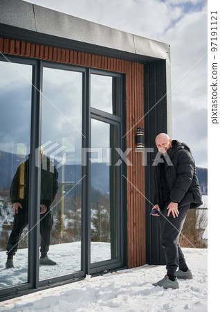 Bald man enjoying weekends on terrace of contemporary barn house. 97191121