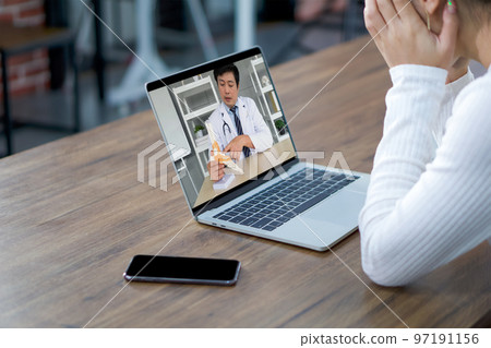 Back view of woman sit at desk at home have webcam conference on laptop computer with Orthopedic Surgeons about foot ankle bone joint. 97191156