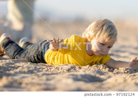Blond little boy lying on the sand Blond little boy lying on the sand 97192124