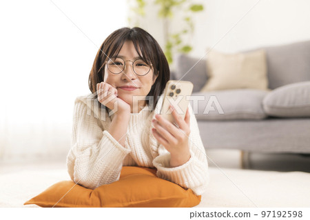 女人在客廳裡看智能手機 女人在客廳裡看智能手機 97192598