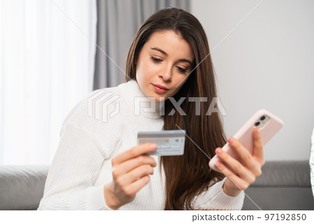 Shot of a young beautiful woman holding a credit card and shopping online. 97192850
