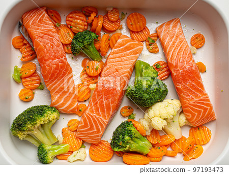 Top view of baking dish casserole with raw uncooked fish salmon steaks, broccoli, cauliflower, carrot. Preparing a healthy dinner concept 97193473