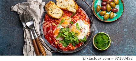 Middle Eastern and Maghrebi healthy dish Shakshouka made of eggs and tomato sauce served in pan Middle Eastern and Maghrebi healthy dish Shakshouka made of eggs and tomato sauce served in pan 97193482