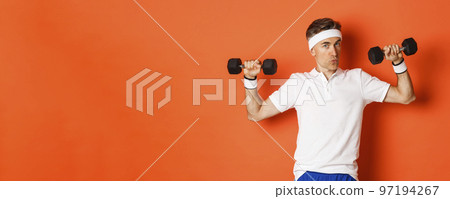 Concept of workout, gym and lifestyle. Image of healthy and strong middle-aged fitness guy, doing sport exercises with dumbbells, standing over orange background 97194267