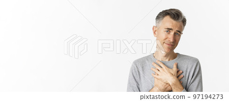 Close-up of thankful middle-aged man, holding hands on heart and feeling touched, appreciate kind gesture, standing over white background Close-up of thankful middle-aged man, holding hands on heart and feeling touched, appreciate kind gesture, standing over white background 97194273
