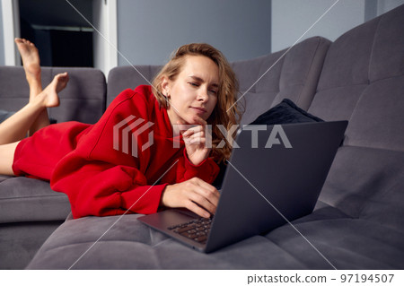 Very tired young woman, burning the midnigh oil - working late at night on her laptop computer, at home, sitting on sofa, rubbing her tired eyes, trying to stay focused. Very tired young woman, burning the midnigh oil - working late at night on her laptop computer, at home, sitting on sofa, rubbing her tired eyes, trying to stay focused. 97194507