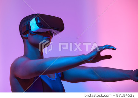 Amazed young woman touching the air during the VR experience. Horizontal studio shot. 97194522