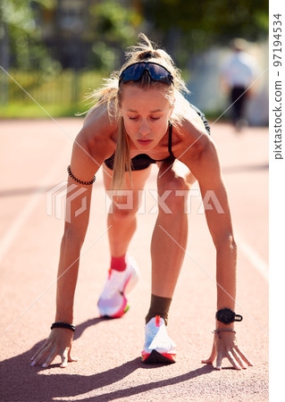Woman getting ready to start on Stadium - summer outdoors training. Woman getting ready to start on Stadium - summer outdoors training. 97194534