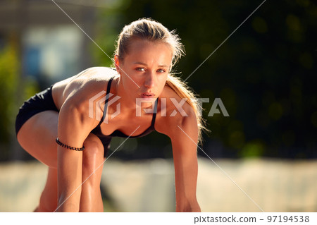 Woman getting ready to start on Stadium - summer outdoors training. Woman getting ready to start on Stadium - summer outdoors training. 97194538