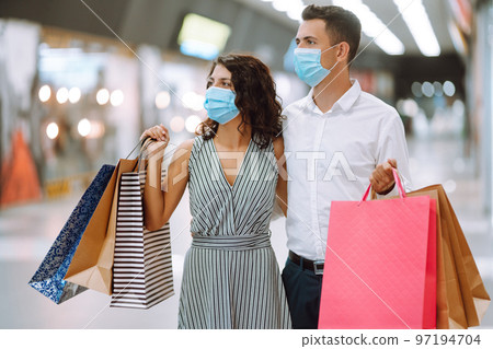 Young couple holding shopping bags, looking upon showcase and discuss shopping inside of mall. Young couple holding shopping bags, looking upon showcase and discuss shopping inside of mall. 97194704