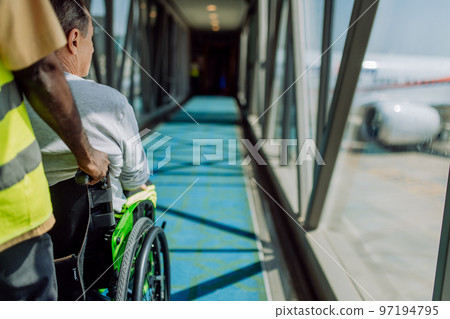 Rear view of airport worker pushing man on wheelchair in the airplane. Concept of traveling with special needs. 97194795