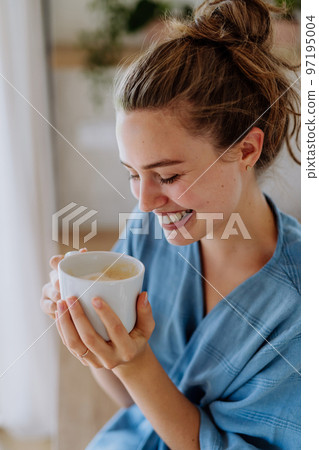 Young woman enjoying cup of coffee at morning, in her kitchen. 97195004