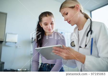 Young woman doctor explaining diagnosis to teenage girl in her ambulance. Young woman doctor explaining diagnosis to teenage girl in her ambulance. 97195063