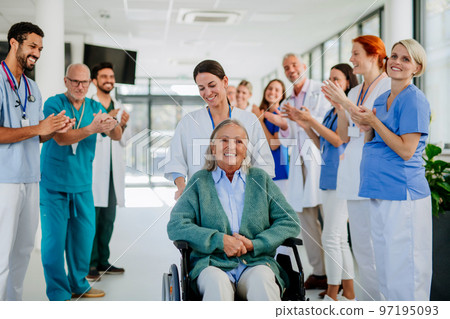 Medical staff clapping to senior patient who recovered from serious illness. 97195093