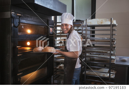 Young baker with chef cap preparing pastries in bakery. Young baker with chef cap preparing pastries in bakery. 97195183