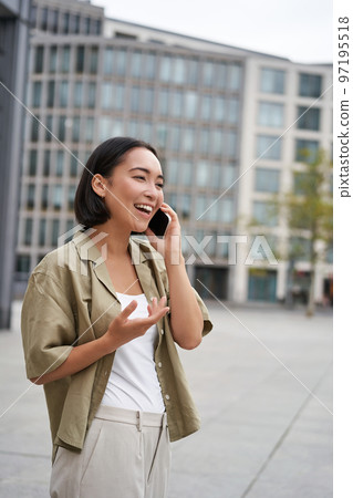 Vertical shot of smiling stylish asian girl, having a telephone conversation and walking on street. Young woman talking on mobile phone Vertical shot of smiling stylish asian girl, having a telephone conversation and walking on street. Young woman talking on mobile phone 97195518