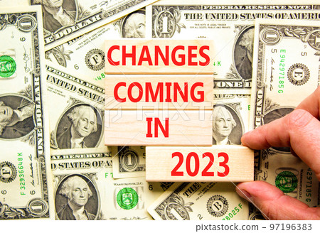 Changes coming in 2023 symbol. Concept word Changes coming in 2023 on wooden blocks. Businessman hand. Beautiful background from dollar bills. Business and changes coming in 2023 concept. Copy space. 97196383